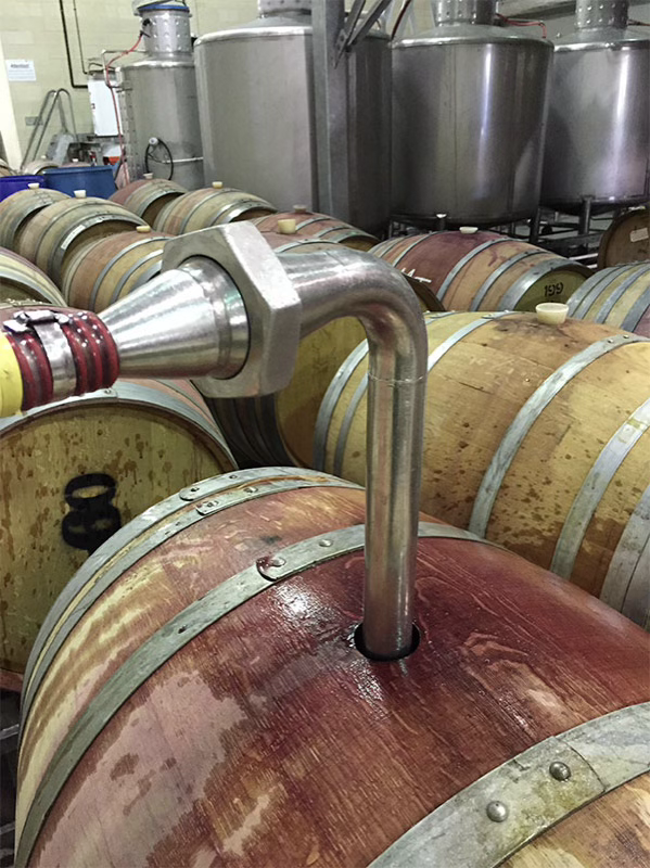 Racking in the cellar Wine being racked between oak barrels through a steel transfer pipe in the cellar at Clos Cien, Rioja, Spain.